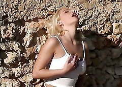 Agreeable golden-haired chick with biggest breasts is playing with her snatch outdoors.