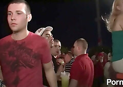 Two college girls share a passionate kiss at a wild party watched by the crowd
