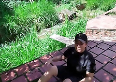 Curvy Brazilian woman bends over on a red-tiled patio as her partner stands behind her