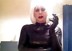 Freaky blonde shemale takes a smoke and teases in rubber