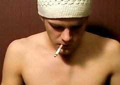 Young gay guy smoking while tugging on his hard cock